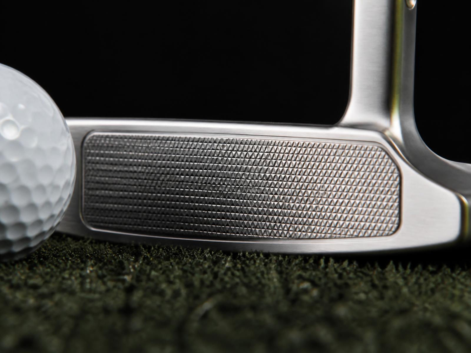 Macro view of a putter face square to the ball at address